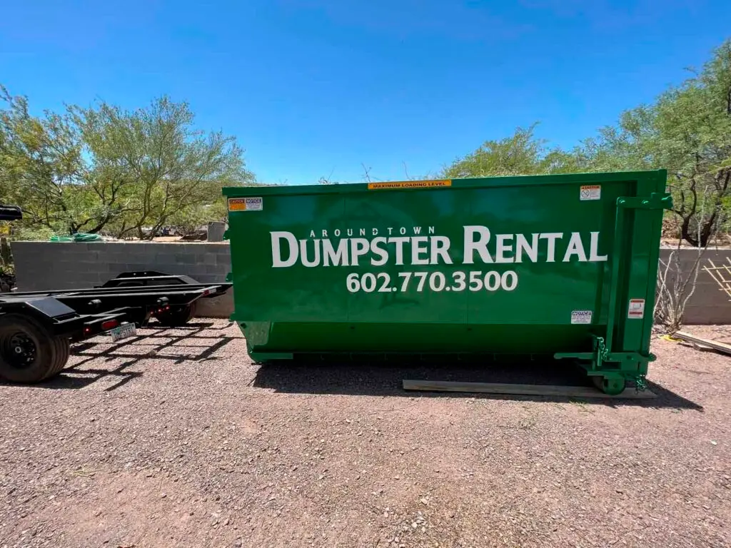Green "Around Town Dumpster Rental" dumpster with phone number 602.770.3500 next to a trailer.